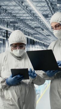 Vertical video EDA engineers in microchip smart factory developing advanced electronics automation process. Experts using simulation software on devices to optimize semiconductor design flow, camera A