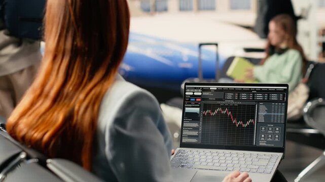Digital nomad woman analyzing financial trends and stock market data on laptop in airport terminal lounge, waiting for flight boarding. Reviewing candlestick charts and forex exchange rates.