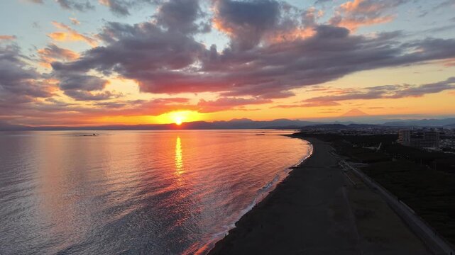 （空撮）富士山と烏帽子岩の間に沈む夕日 in 湘南海岸
