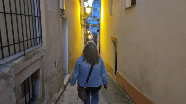 Woman walking down a narrow european alley at dusk