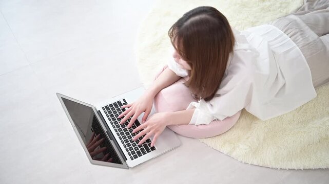 自宅でパソコンを使いながらタイピングする在宅勤務やリモート勤務や資格の勉強をする女性のデザイナーやフリーランスのビジネスイメージ　俯瞰