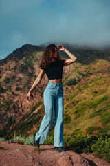 Naklejka premium Brunette woman with wavy hair and athletic figure posing with Kyrgyzstan mountains