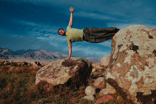 Man doing side plank on rocks in Kyrgyzstan mountains