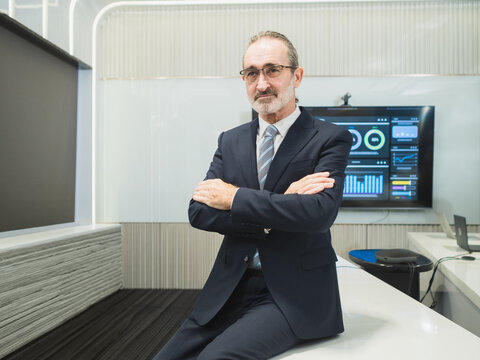 Confident Senior Executive Modern Digital Office. professional senior businessman suit sits confidently high-tech conference room data dashboards, symbolizing experienced leadership corporate success.