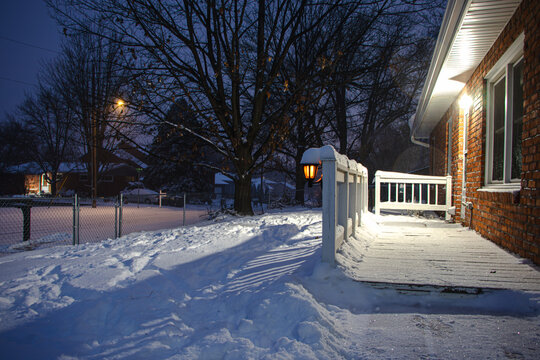 A quiet winter yard in a quiet neighborhood covered in snow as night begins to fill the sky