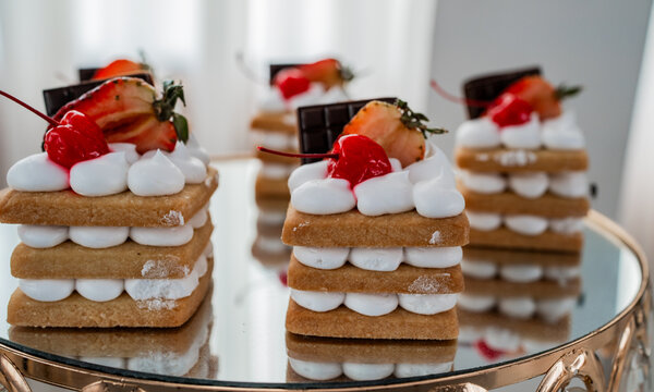 Postres gourmet con crema, fresa y chocolate sobre base de galleta en elegante presentaci&oacute;n