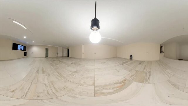 A spacious, bright, empty room with a large overhead light, tiled floor, and curved walls