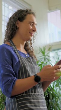 Non-binary plant staff tapping phone causing animated icons tagging pots while answering client