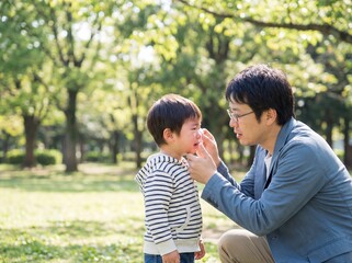 Fototapeta premium Caring Japanese Father Comforting Crying Toddler Son in Park