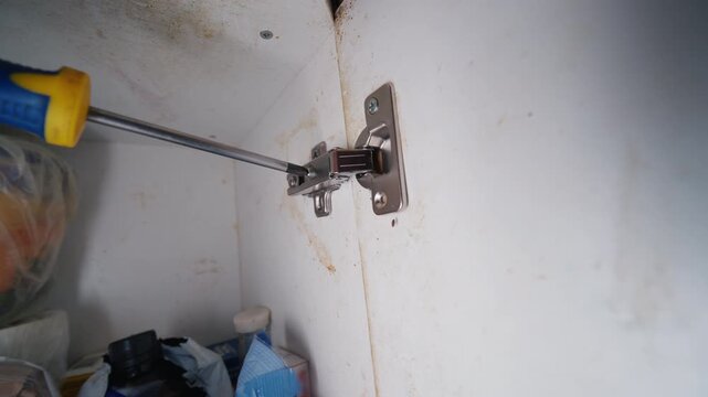 Handyman Adjusting Cabinet Door Hinge with Screwdriver Close-Up Shot | DIY Hinge Alignment and Furniture Repair Concept