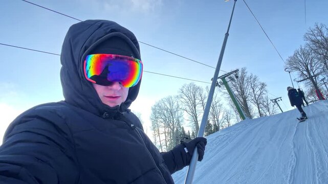 Person on ski lift wearing goggles, enjoying winter sports on snowy day