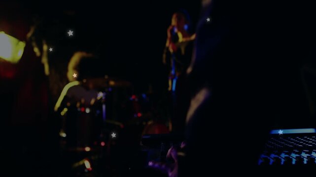 Mixer hand adjusting faders starting camera pullback showing band performing while stars growing