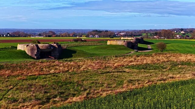 Aerial view of the Longues-sur-Mer Battery in Normandy, France, showing preserved World War II gun casemates set in open fields under clear coastal light.