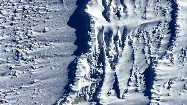 Aerial top down texture of wind shaped snow drifts and frozen surface in winter landscape