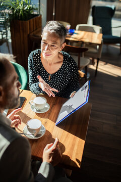 Senior advisor meeting client over coffee in cafe