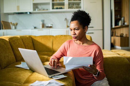 Focused woman paying bills on laptop at home