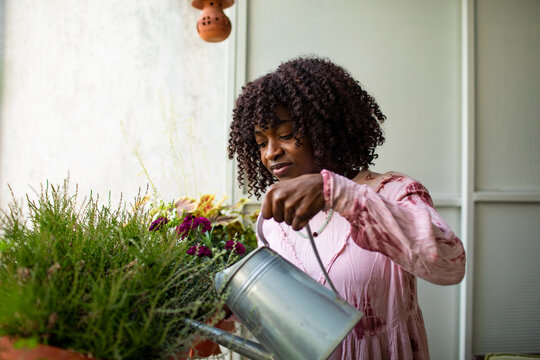 Woman watering potted plants on home balcony