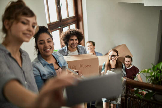 Young friends carrying moving boxes in apartment stairwell