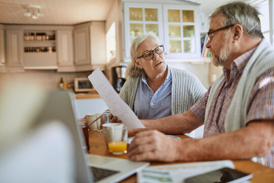Senior couple discussing household finances at kitchen table