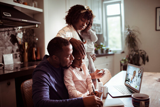 Parents consult online doctor at home with sick child in kitchen