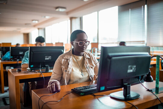 Focused student using desktop computer in university computer lab