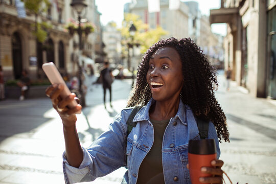 Surprised young woman video chatting on city street