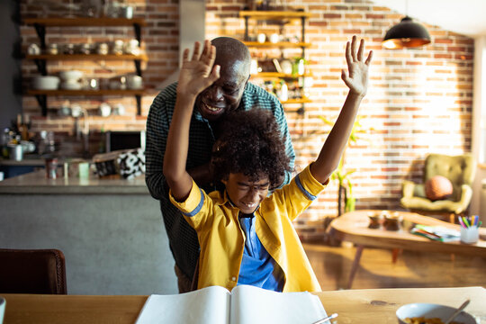 Happy father and son celebrating homework success at home