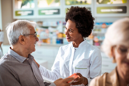 Pharmacist assisting senior customer in modern pharmacy