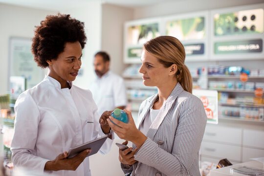 Pharmacist advising customer on product in modern pharmacy