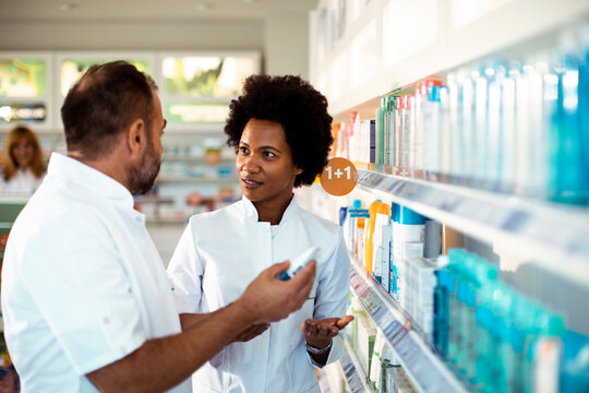 Pharmacists discussing medication options in pharmacy aisle