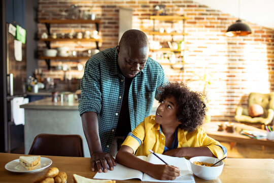 Father helping son with homework at the kitchen table