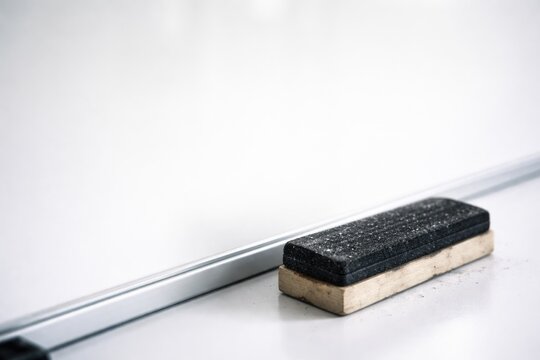 Close up of a blackboard eraser resting on a whiteboard surface with ample copy space
