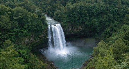 Fototapeta premium Stunning waterfall cascading through a dense green forest creating a beautiful natural backdrop