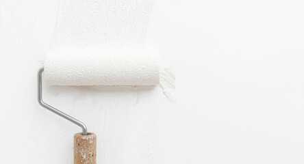 Obraz premium Macro image of paint roller covering spotless wall in white paint with copy space for text