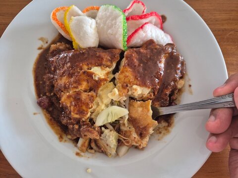Indonesian tahu telur with peanut sauce, fried tofu egg dish served with crackers and vegetables