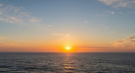 Obraz premium Morning ocean view with rising sun and gentle white clouds in sky
