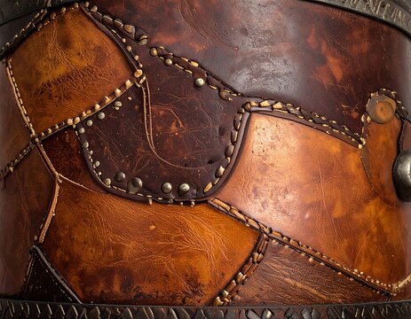 Close-up of a decorative leather object, featuring patched sections with metal studs and stitching