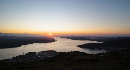 Fototapeta premium Calm sunrise view of port and surrounding mountain terrain