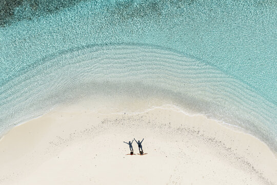 Aerial top down view of couple on white sand beach in the Maldives