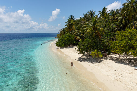 Aerial view of young woman at the beach on an island in the Maldives