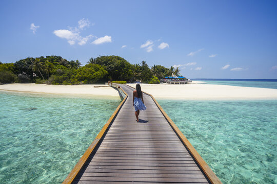 Young asian woman walking on jetty on an island in the Maldives