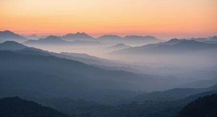 Obraz premium Softly misted mountains at daybreak offering a peaceful and rejuvenating nature view