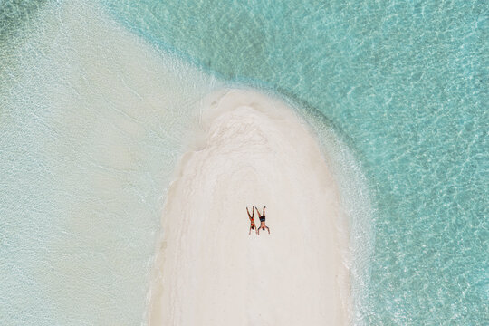 Aerial top down view of couple lying down on a beach in the Maldives