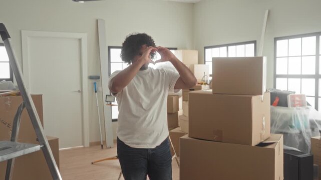 Man forms heart with hands above packed moving boxes in building during unpacking and setup; new beginning hopeful.