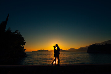 Fototapeta premium Lovers at sunset. Couple sharing intimate moment at twilight near islands and waves