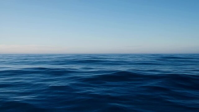 Calm deep blue ocean surface under hazy sky with soft waves and horizon water