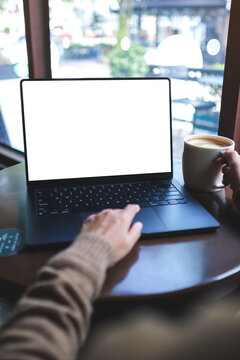 Vertical mockup image of a woman working on laptop computer with blank white desktop screen while drinking coffee in cafe