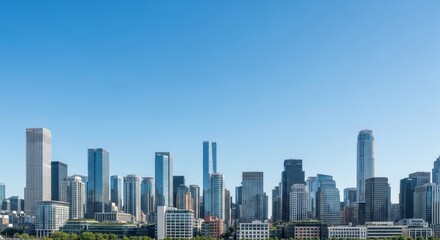 Obraz premium Bright daytime panoramic skyline of a modern city, tall glass towers against a clear blue sky, with distant trees suggesting balance between nature and development