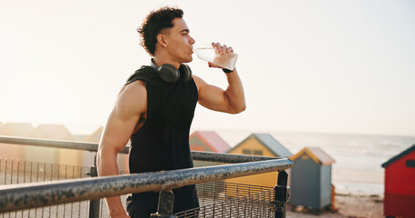Beach, fitness and man with water on break, reflection and drinking liquid after training in nature. Outdoor, space and person with bottle for wellness, exercise and cool down with mineral hydration © peopleimages.com