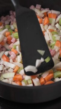 Stirring pancetta with onion carrot and celery on pan